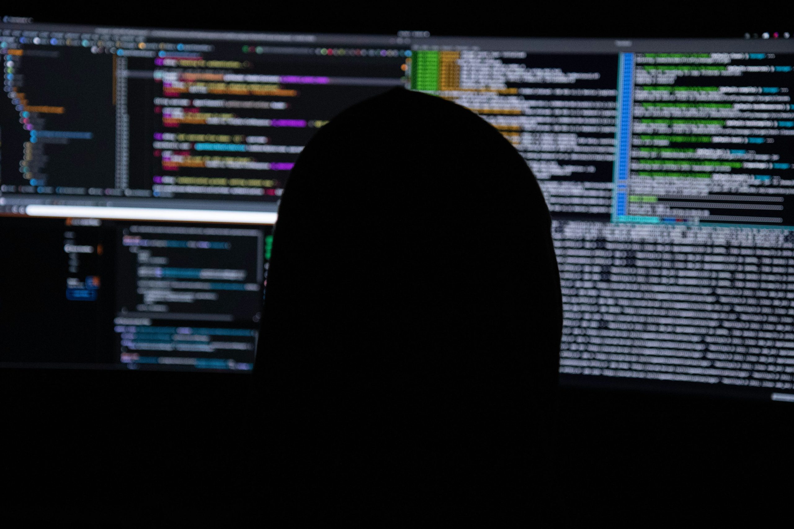 Hacker in front of computer screens with code