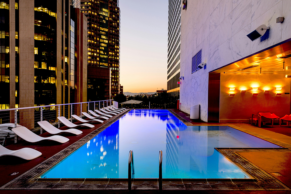 Luxury hotel rooftop pool with city skyline view at sunset