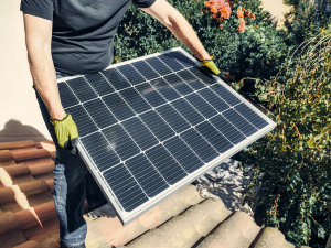 Person handling a solar panel, illustrating solar power setups for remote security.