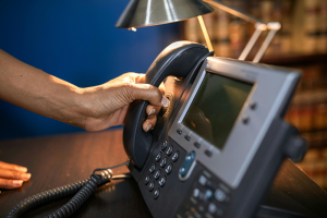 Person picking up a desk IP phone.