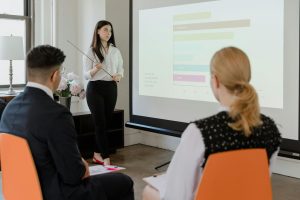 Person presenting a bar chart to colleagues in a meeting room.