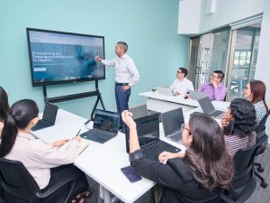 Team meeting in a small conference room with a presenter using a large interactive screen