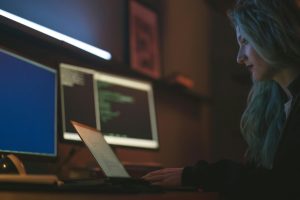 Woman working at a computer with multiple screens showing code