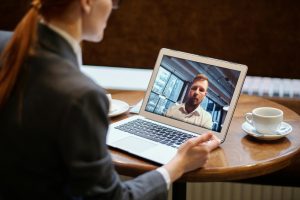Business professional joining a video meeting on a laptop in a café setting