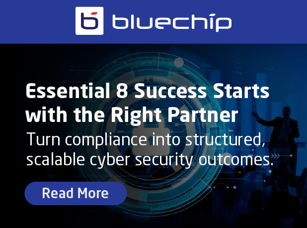 Bluechip IT promotional graphic. The logo for "bluechip" sits at the top against a navy blue header. Below, a digital circular HUD and padlock icon are overlaid on a background of a professional setting. Large white text reads: "Essential 8 Success Starts with the Right Partner. Turn compliance into structured, scalable cyber security outcomes." A blue "Read More" button is at the bottom left.