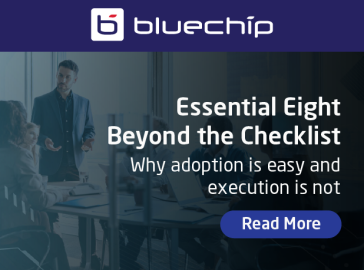 A promotional banner for "bluechip" featuring a background of a professional meeting in an office. The text reads: "Essential Eight: Beyond the Checklist – Why adoption is easy and execution is not," accompanied by a "Read More" button.