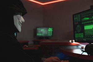 Masked hacker targeting systems, highlighting Essential 8 cyber threats.