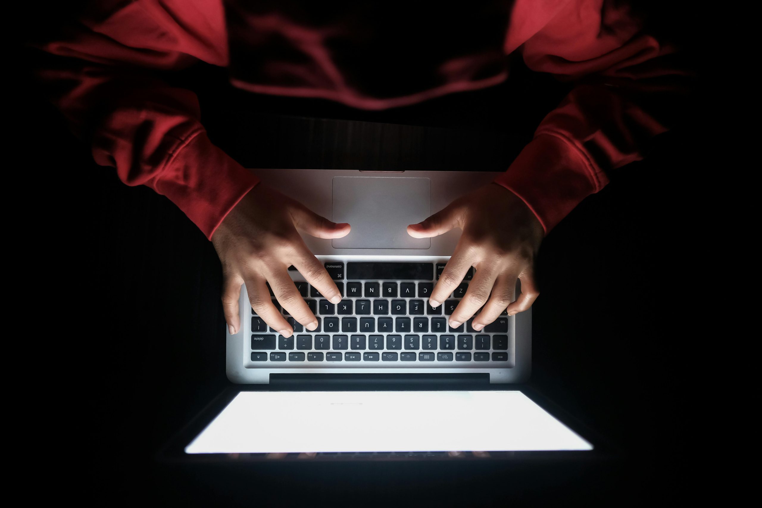 Person typing on laptop in dark, representing cybersecurity threat.